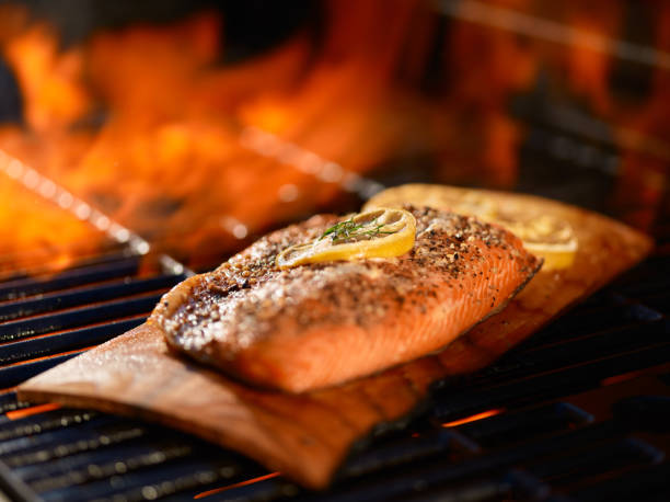 Salmon Cooking On Cedar Plank Over Open Flame On Grill